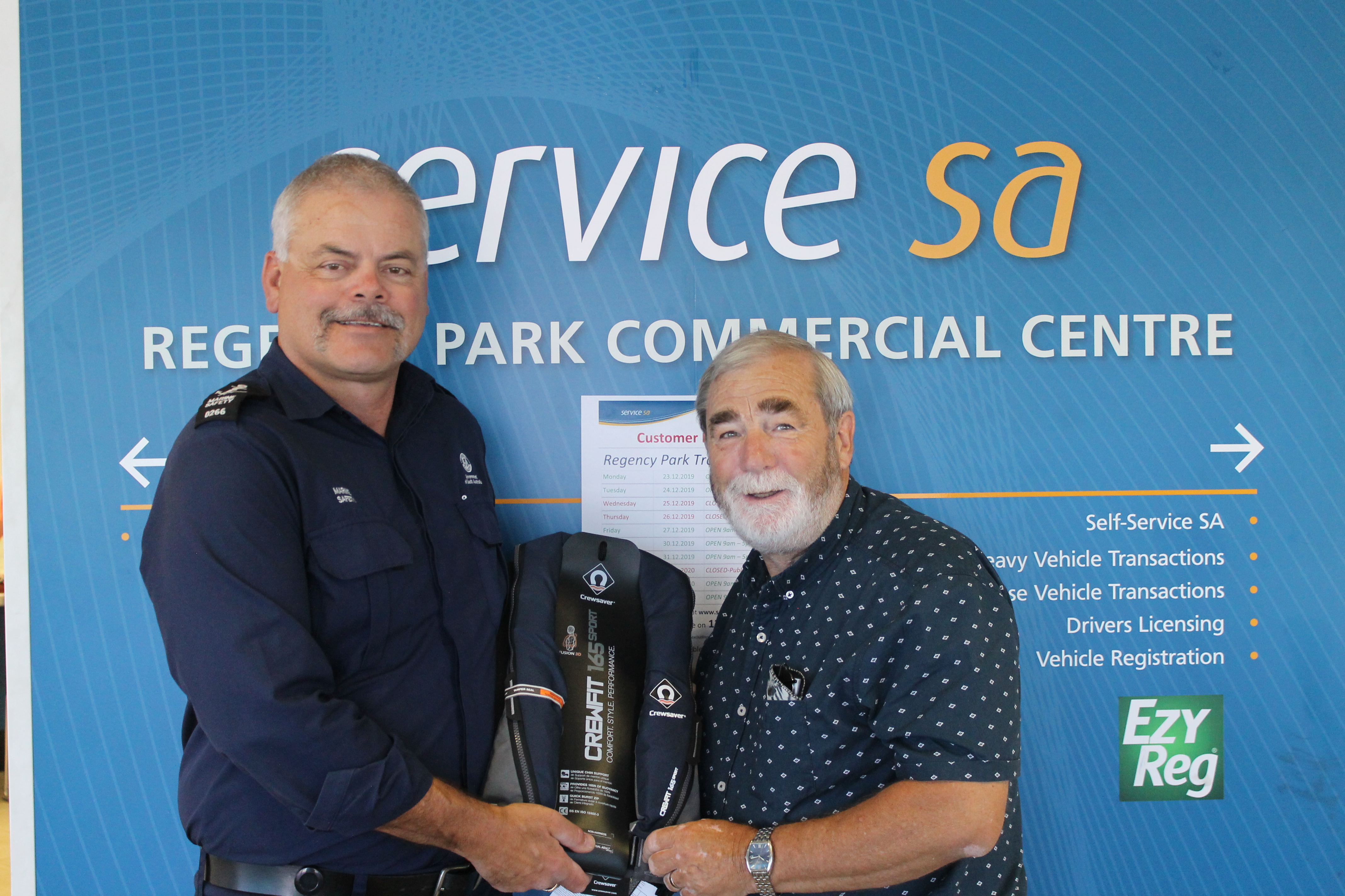 Photo of the third boating safety survey winner, Graham Peach, being presented with his lifejacket prize