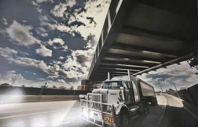 Stylised photo of a semi-trailer going under the new bridge on the construction site